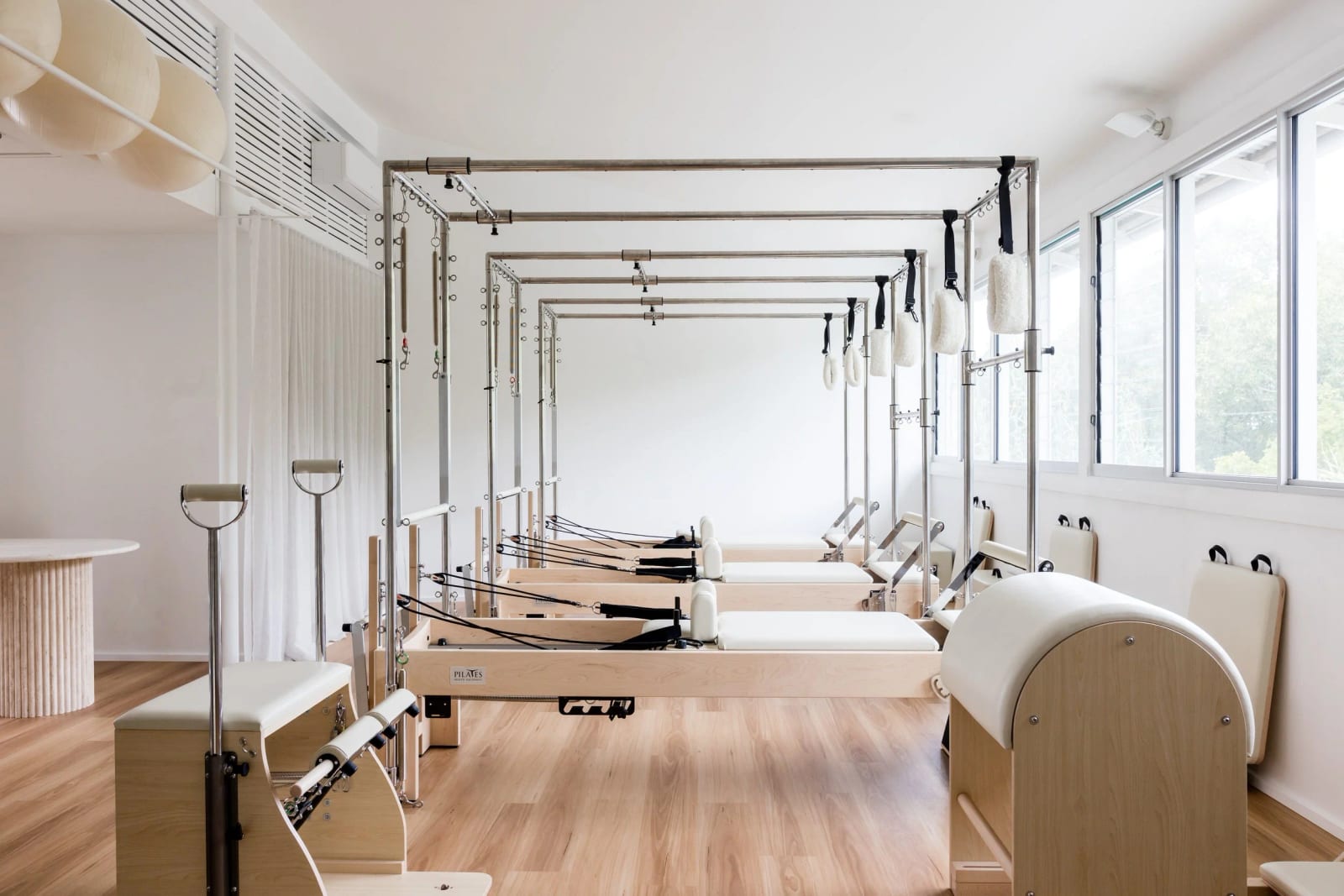 Estúdio de Pilates vazio e acolhedor com aparelhos alinhados, plantas e luz natural